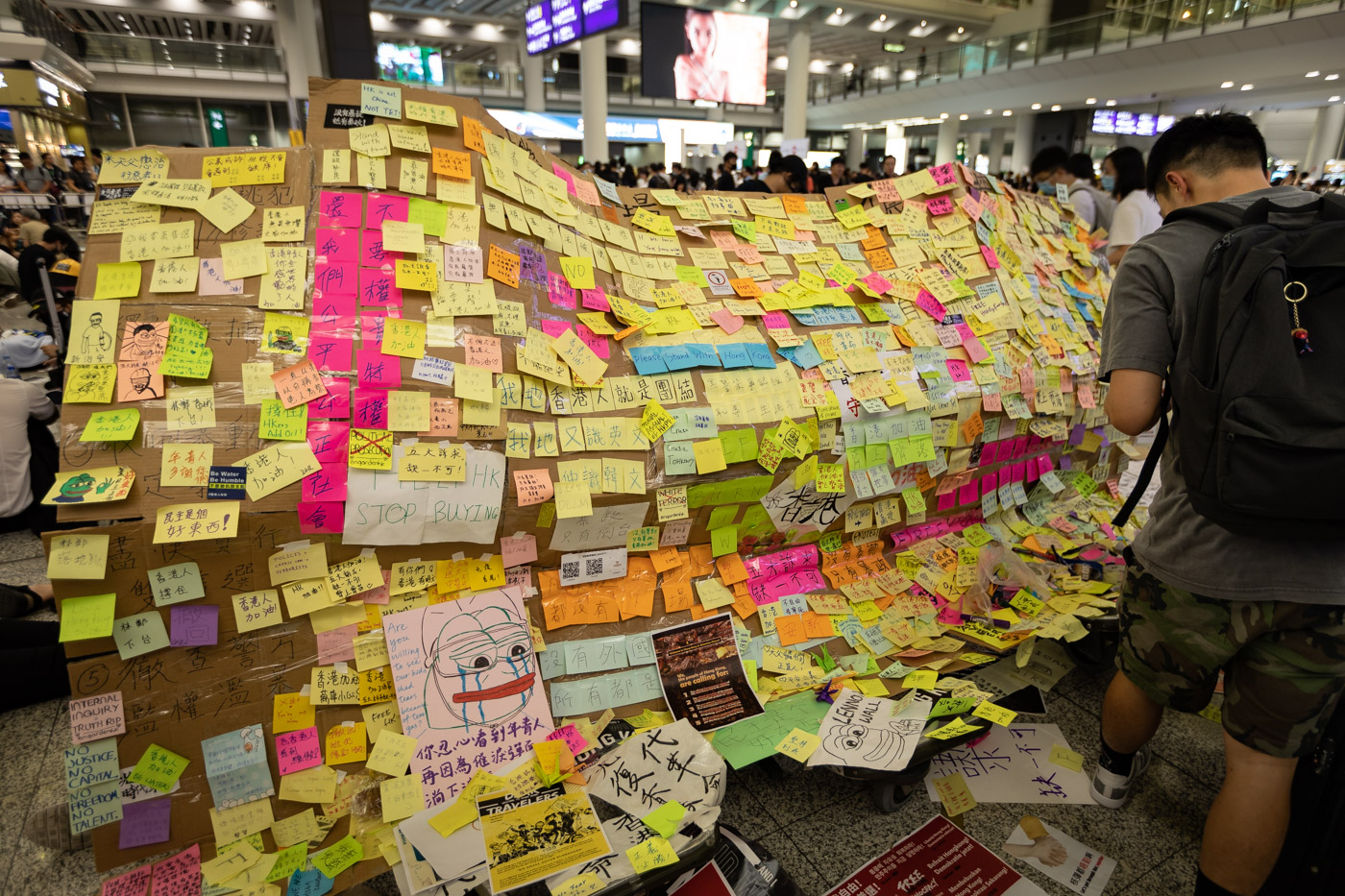 A makeshift Lennon Wall covered in multicolored sticky notes, each with a protest message.