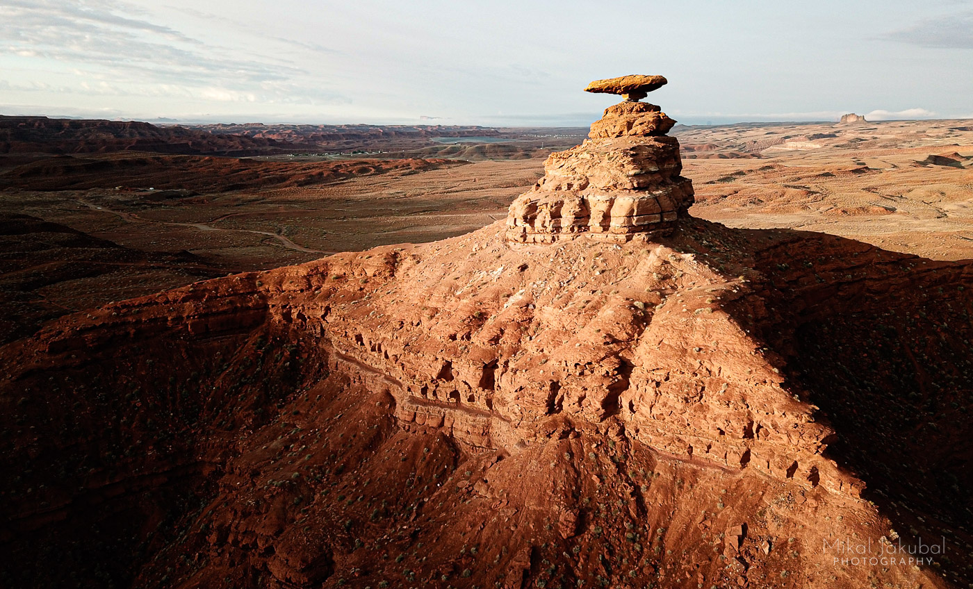 A barren sandstone ridge supports a flat-topped, hat-like balanced rock at its summit.