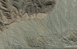 Satellite image of desert landscape showing yellow pin with GPS coordinates.