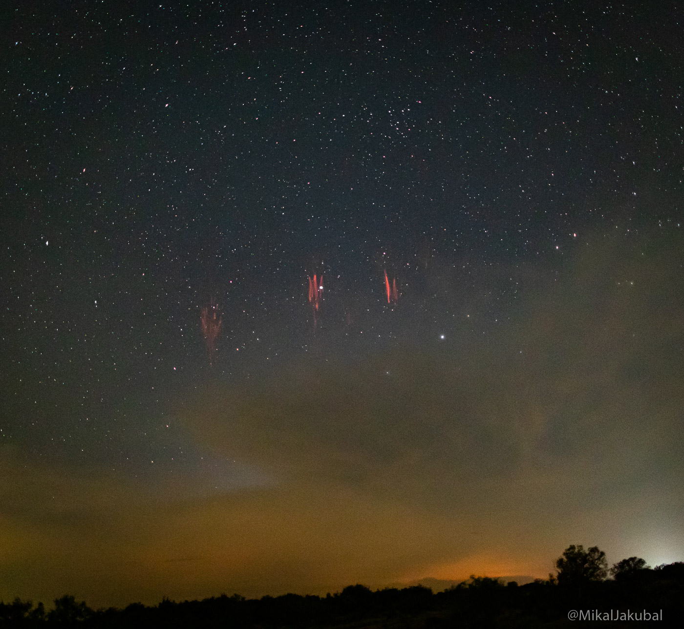 Sprites or sprite lightning. Several red bursts, like small fireworks, appear in the night sky.