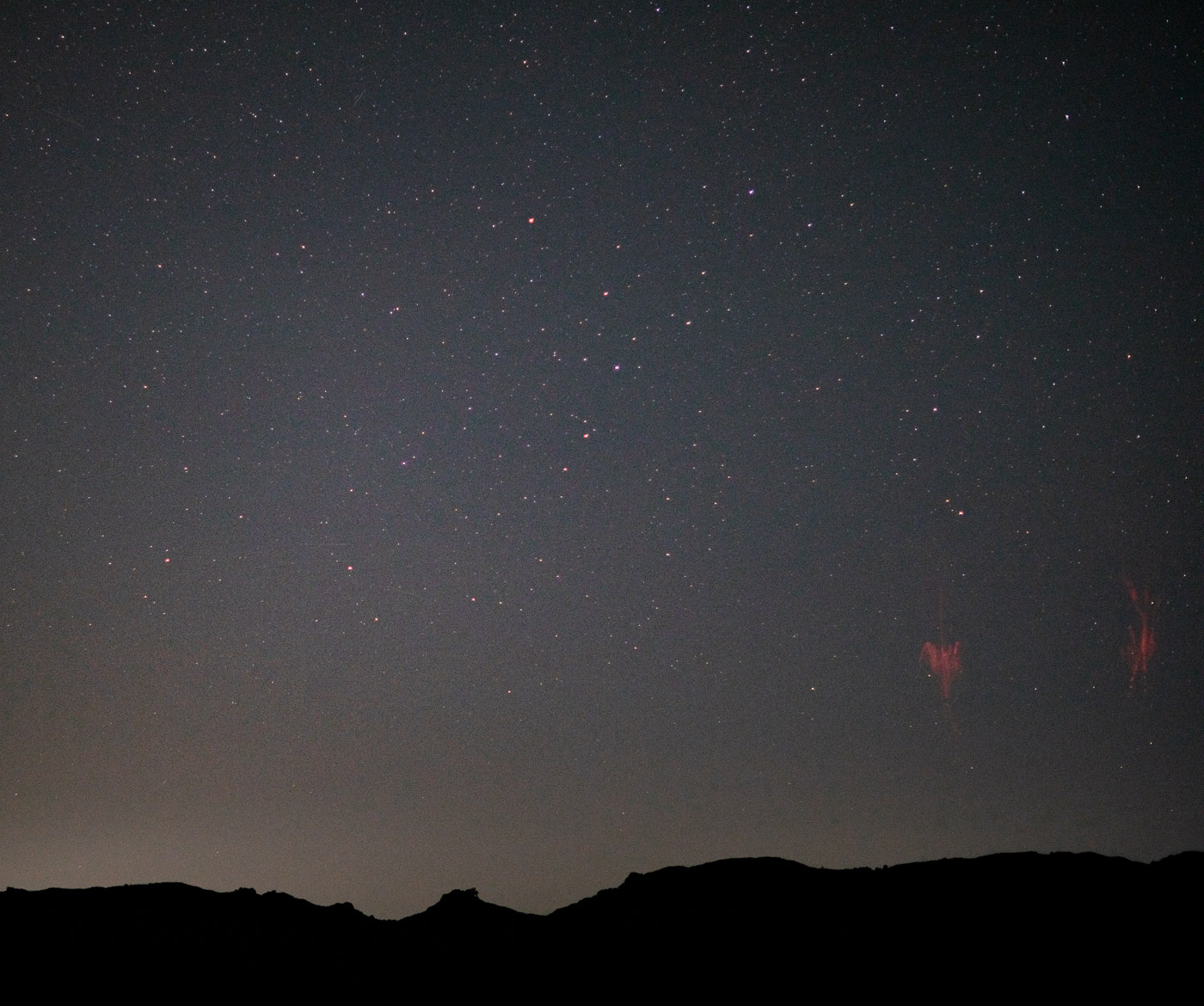 Sprites or sprite lightning. A red burst, like small fireworks, appear in the night sky.